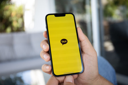 Alanya, Turkey - September 20, 2023: Man hand holding iPhone 14 with social networking service messenger Kakao Talk on the screen.のeditorial素材