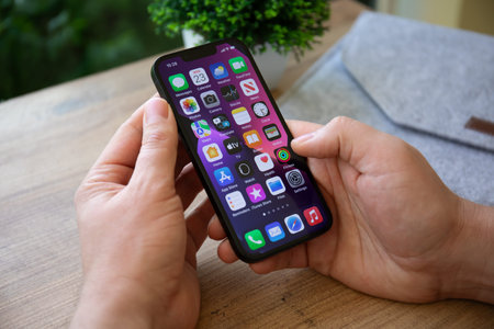 Alanya, Turkey - February 23, 2022: Man hand holding iPhone 13 with home screen IOS 15 on the...