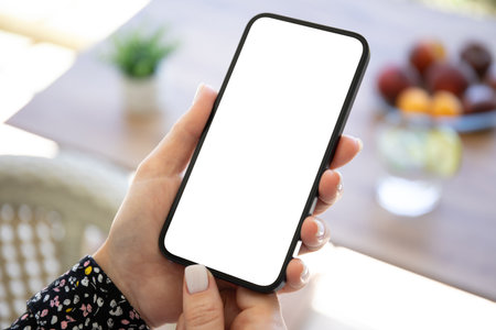 female hand hold phone with isolated screen background of table in cafeの写真素材