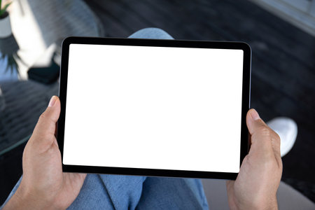 Male hands holding computer tablet with isolated screen on background of cafe in officeの写真素材