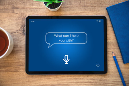 computer tablet with app personal assistant on screen background wooden table with blue notepad in officeの写真素材