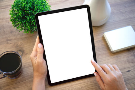 female hands hold computer tablet with isolated screen background wooden table in officeの写真素材