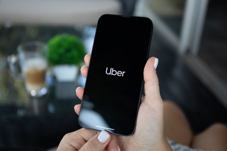 Alanya, Turkey - October 5, 2023: Woman hand holding iPhone 14 with application Taxi Uber on the screen.のeditorial素材