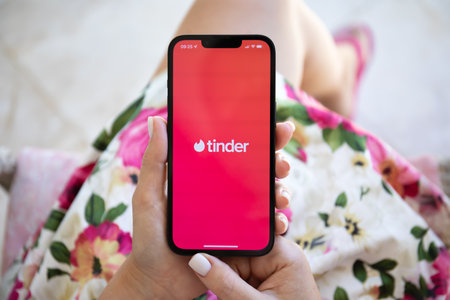 Alanya, Turkey - July 27, 2022: Woman hands holding iPhone 13 with online Internet network service Tinder on the screen.のeditorial素材