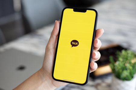 Alanya, Turkey - October 24, 2023: Woman hand holding iPhone 14 with social networking service messenger Kakao Talk on the screen.のeditorial素材