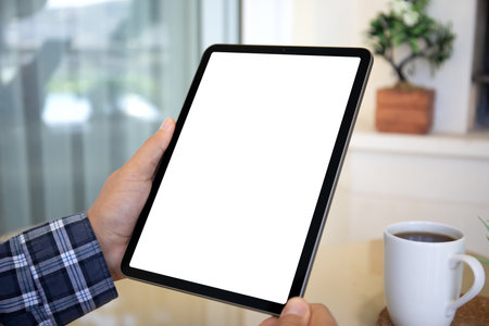 male hands holding computer tablet with isolated screen on background of interior in houseの写真素材
