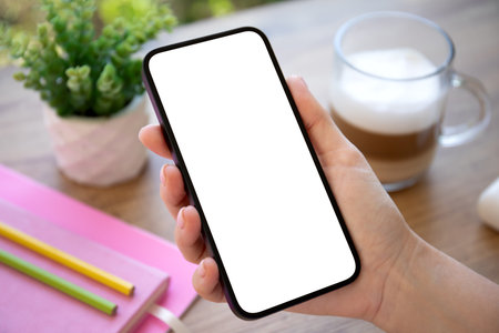 woman hand hold phone with isolated screen background pink notepad on table in officeの写真素材