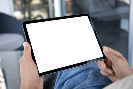 Male hands holding computer tablet with isolated screen on background of cafe in officeの写真素材
