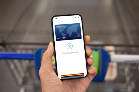 man hand hold phone with face scanning ID on the screen over shopping cart in supermarketの写真素材