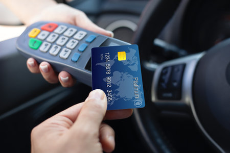 man hand holding plastic card and pay pass online terminal background car steering wheelの写真素材