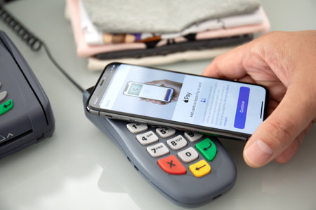 Alanya, Turkey - August 12 2019 : Man hand holding Apple iPhone X with Apple Pay on the screen and POS pay pass online terminal. iPhone was created and developed by the Apple inc.のeditorial素材