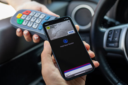 Alanya, Turkey - November 7, 2023: Man hands holding Apple iPhone 14 with Apple Pay on the screen. iPhone, Apple Pay and Car Play was created and developed by the Apple inc.のeditorial素材