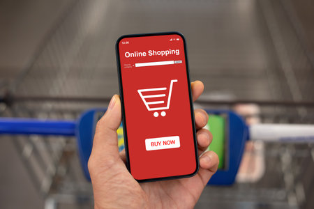 male hand hold phone with app online shopping on screen over shopping cart in the storeの写真素材