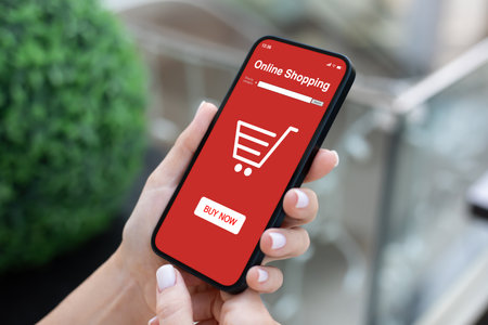 woman hand hold phone with app online shopping on screen background of green street with storeの写真素材