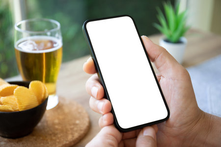 Man hand hold phone with isolated screen background of table with beer and chips in cafeの写真素材