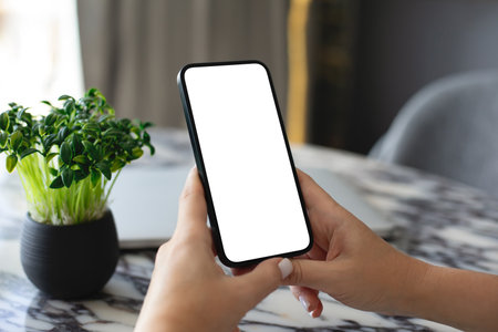 Female hand hold phone with isolated screen background of table in the officeの写真素材