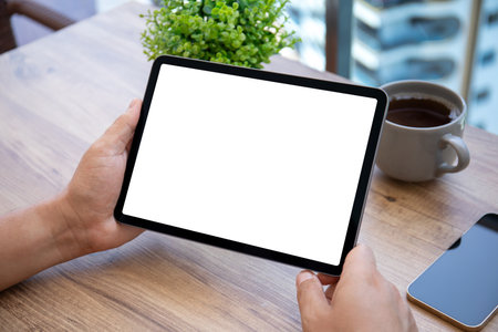 male hand hold computer tablet with isolated screen background of table in cafe officeの写真素材
