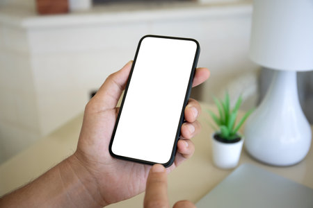 Male hand hold phone with isolated screen background of table at homeの写真素材