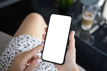 woman hand hold phone with isolated screen background of cafe officeの写真素材