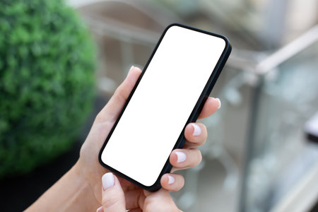 woman hand hold phone with isolated screen background of green streetの写真素材