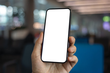Male hand holding phone with isolated screen on blue office backgroundの写真素材