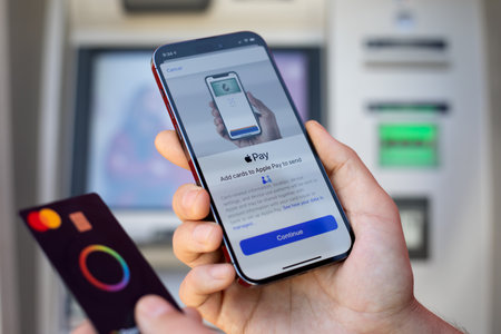 Alanya, Turkey - March 12, 2024: Man hand holding iPhone 15 Pro Max with app Apple Pay Cash on the screen and card Mastercard. iPhone 15 was created and developed by the Apple inc.のeditorial素材