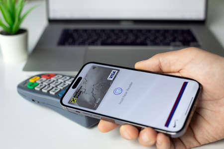 Alanya, Turkey - April 4, 2024: Man hand hold Apple iPhone 15 Pro Max with app Apple Pay Raiffeisenbank on the screen and pay pass online POS terminal buy clothes in the shop.のeditorial素材