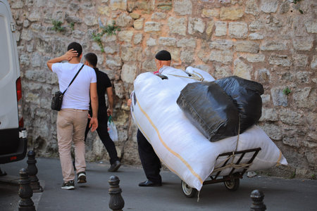 A man carries a large cart with goods on the street
