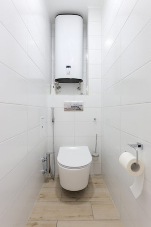 White toilet bowl with electric boiler in a bathroom interior