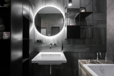 Round illuminated mirror and washbasin in the bathroom interiorの写真素材