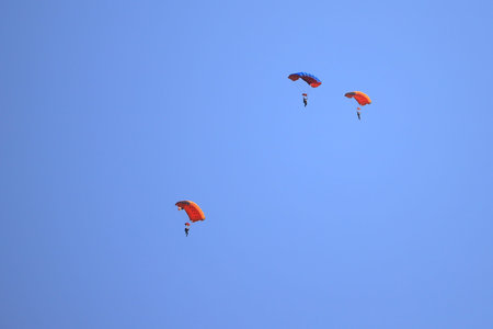 Skydivers descends on a parachute against the blue sky