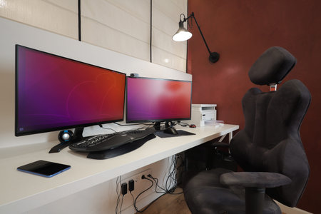 IT workplace with two monitors and armchair at homeの写真素材