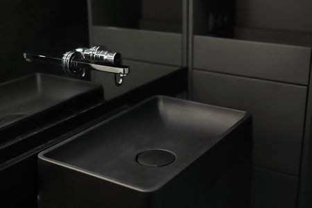 Chrome faucet with black ceramic sink close-up in the bathroom interior