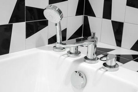 Chrome faucet with shower head close-up over bathtub