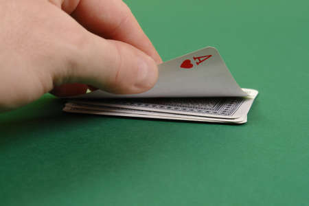 Gambler hand revealing ace of hearts on green tableのeditorial素材