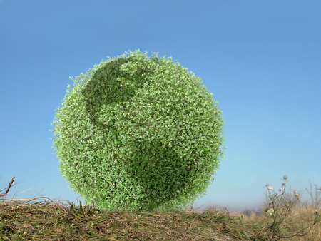 Green globe with american continents resting in grass over clear blue skyの写真素材
