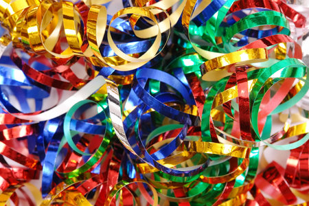 Closeup of twisted and tangled party streamers in blue, silver, red, green and golden colorの写真素材