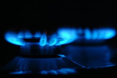 Closeup of two gas cooker burners lit in the darknessの写真素材