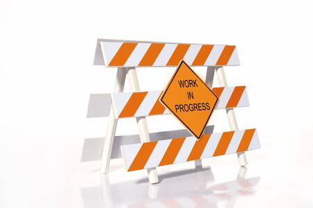 Orange and white striped road construction barrier with Work in Progress sign over white backgroundの写真素材