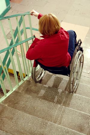 Handicapped woman on wheelchair going downstairs in building staircaseの写真素材