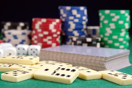 Pile of domino pieces, deck of playing cards, dices and casino chips on green tableclothのeditorial素材