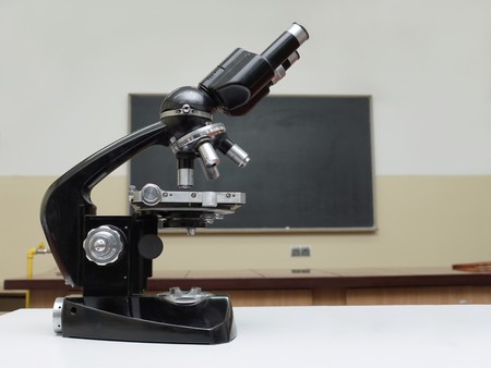 Old school microscope in classroom with blackbroard in the backgroundの写真素材