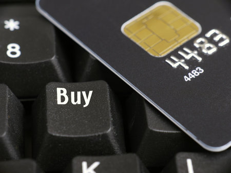 Closeup of black microchip credit card and computer keyboard key spelling Buy word