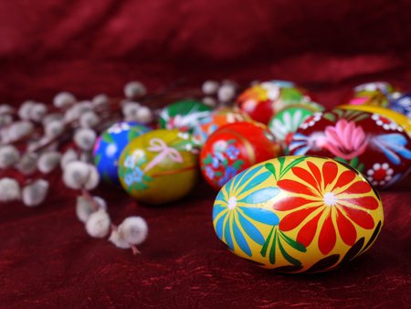 Painted Easter eggs and bunch of pussy willow branches on scarlet fabric