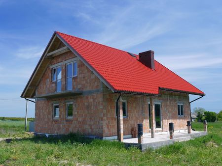 Unfinished single-family brick house covered by red sheet metal roofの写真素材