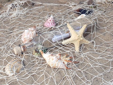Starfish, seashells and bottle with message caught in the fishing netの写真素材