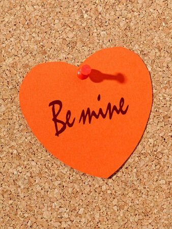 Red paper heart with Be mine text pinned to the corkboardの写真素材