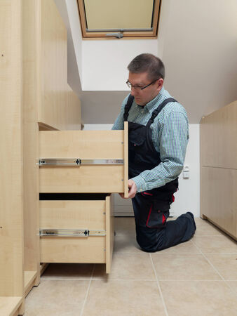 Carpenter installing wardrobe drawers in walk-in closetの写真素材