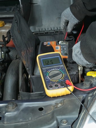 Auto mechanic measuring car battery voltage using multimeterの写真素材