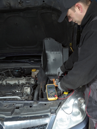 Auto mechanic measuring car battery voltage using multimeterの写真素材